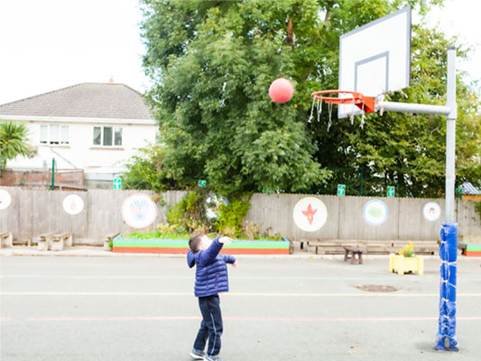 Boy playing basketball in school yard