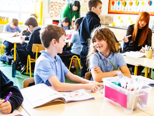 Boy and girl laughing during school lesson