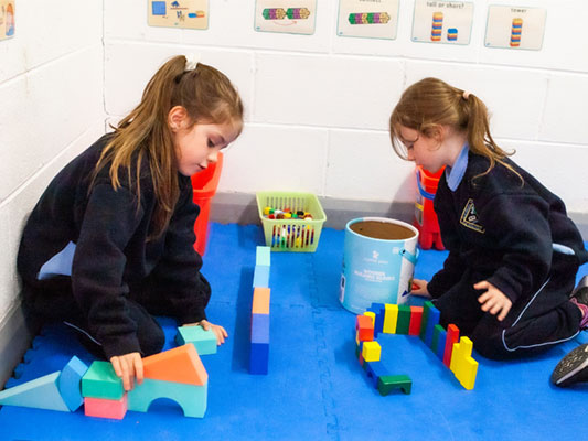 Two girls plaing with blocks on the floor